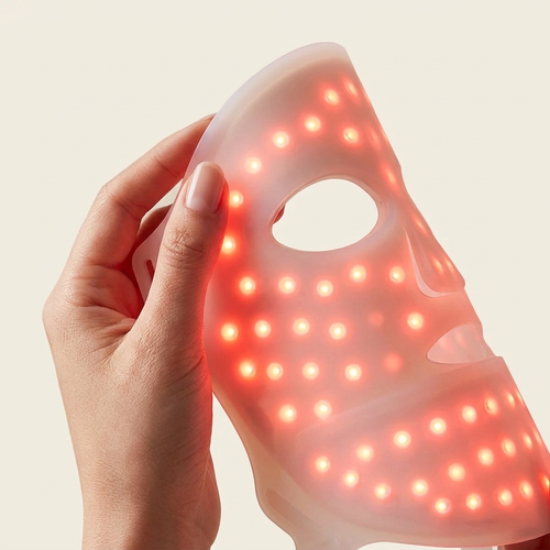 PURE SOL. silicone LED mask glowing warm red light, held in hand